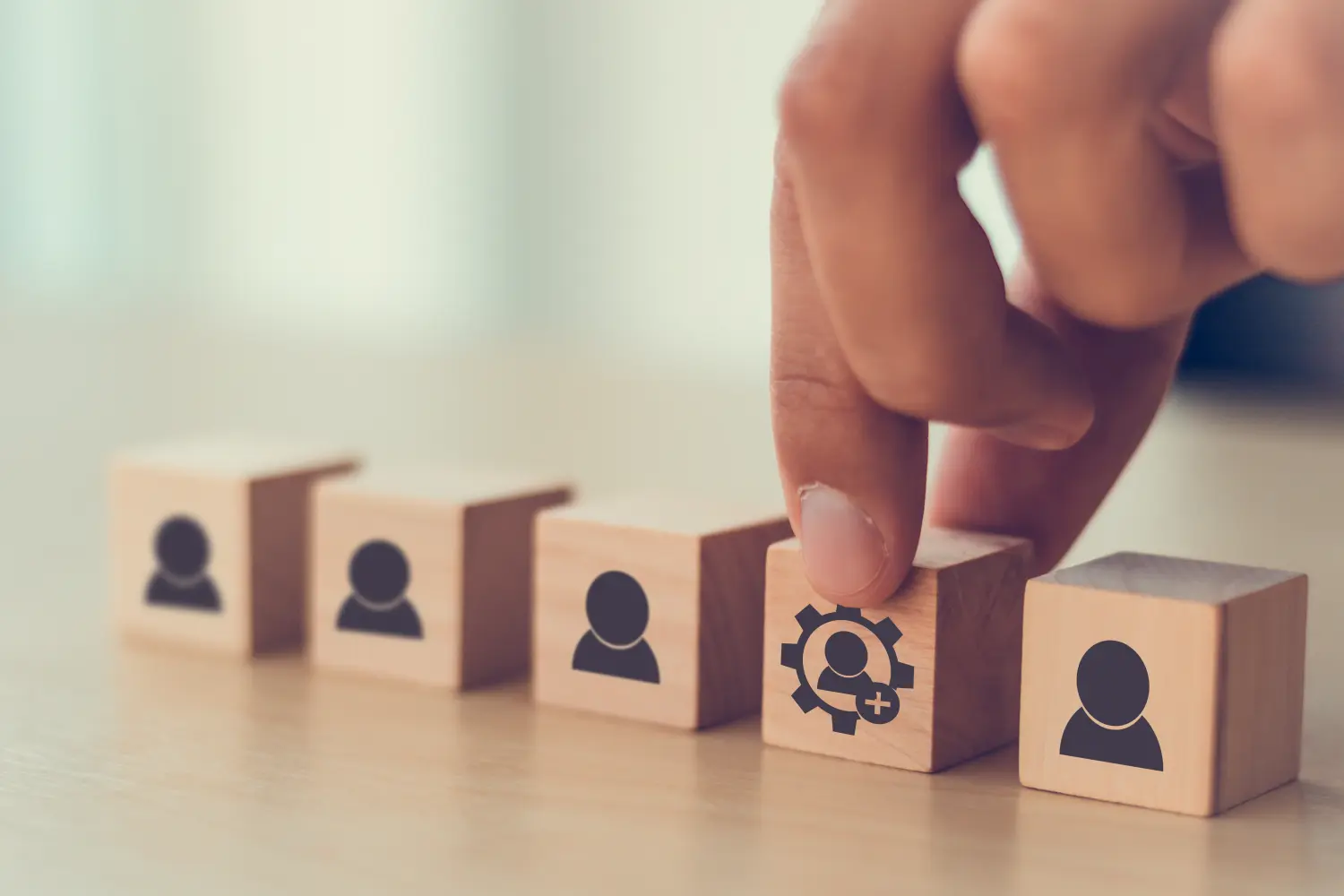 Der Mann hält einen Holzwürfel mit dem Symbol für neue Fähigkeiten auf dem Symbol für viele Mitarbeiter